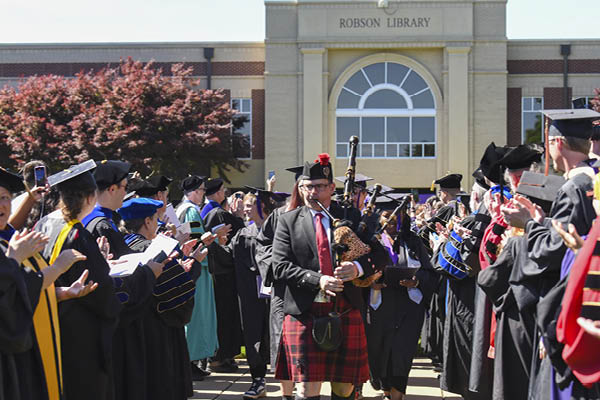 Bagpiper leads students during Commencement 2025