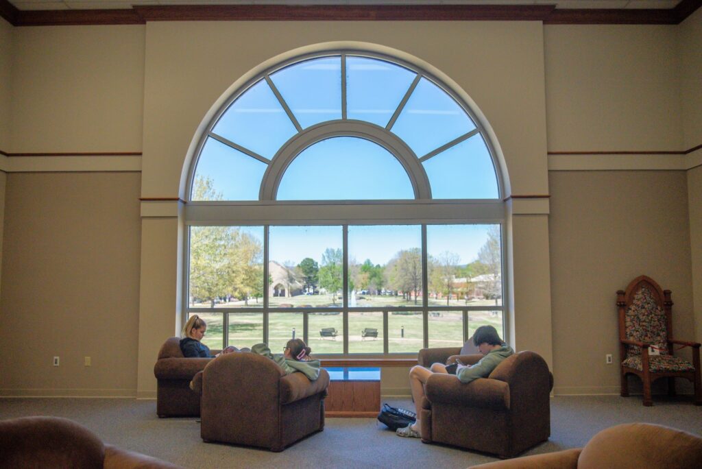 Students sitting in front of Library picture window